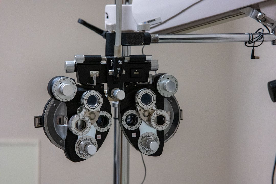 A phoropter with multiple circular lenses mounted on a stand for eye examinations.
