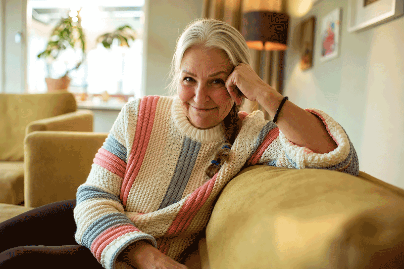 An older woman looks toward the camera while relaxing at home after learning about macular degeneration treatment from Aiello Eye Institute.